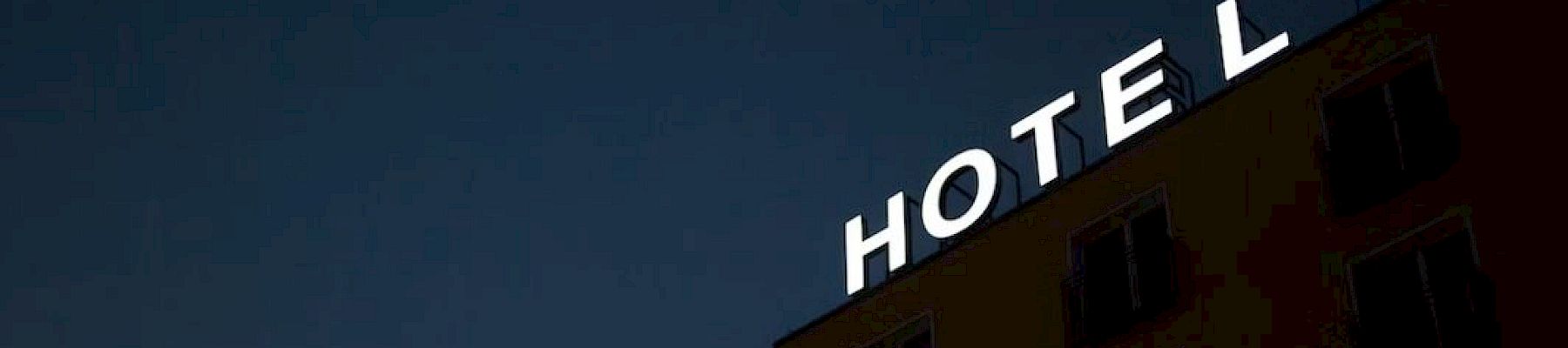The image shows a building with a sign that reads "HOTEL" against a dark sky, with the "L" slightly separated, viewed from below.
